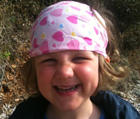 Foto von einem kleinen MÃ¤dchen mit bunten Kopftuch und schelmischem Lachen